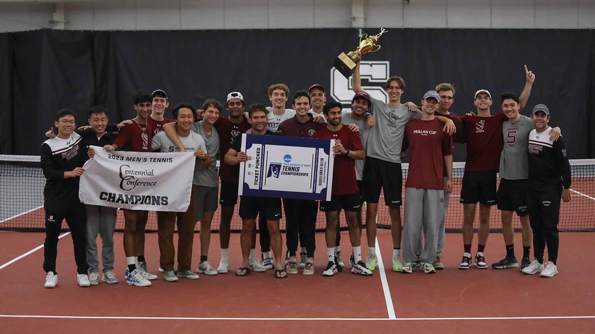 The Swarthmore men's tennis team celebrating with its 2023 conference championship trophy and NCAA tournament ticket.